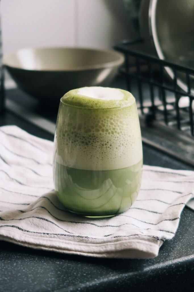 Delicious frothy matcha latte placed on a striped tea towel in a cozy London kitchen.