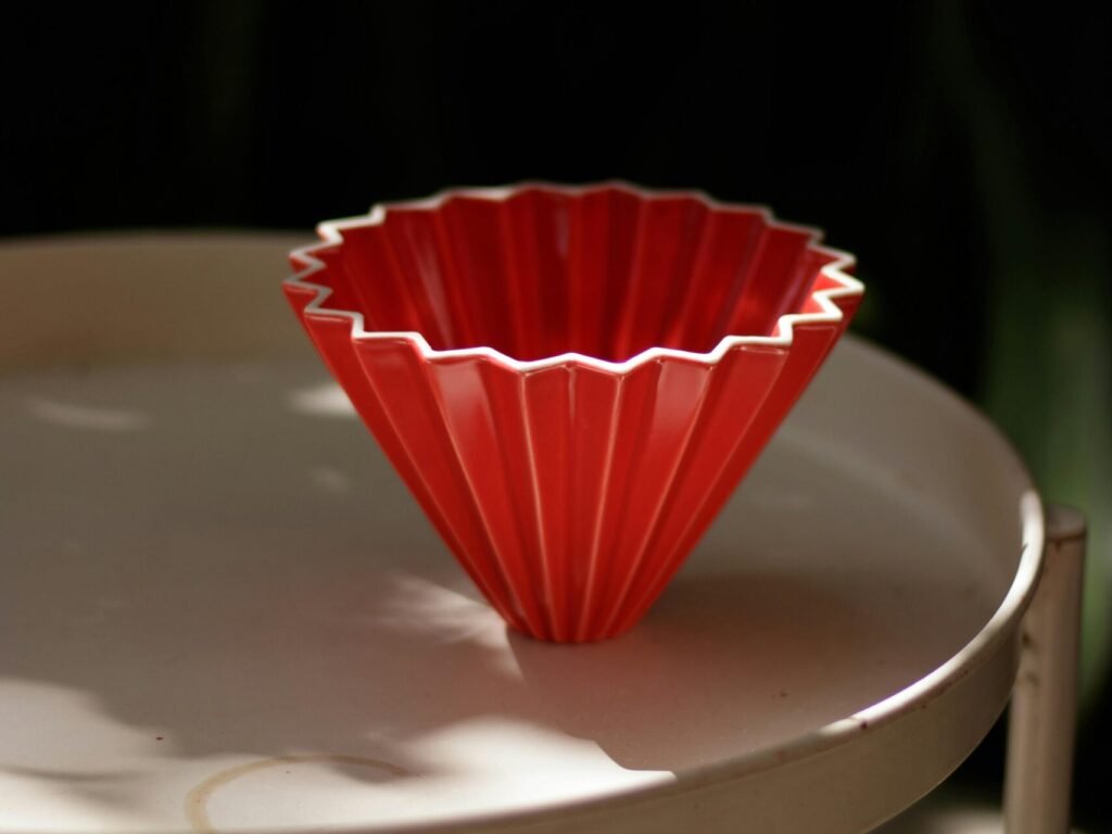 A red origami-style coffee filter sits elegantly on a white table.