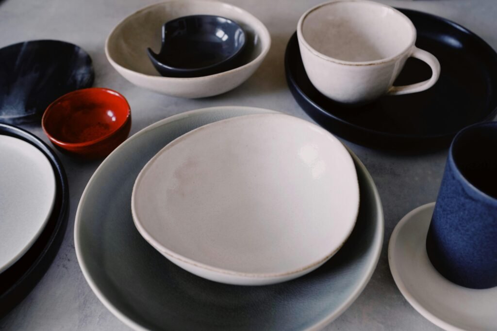 A variety of stylish ceramic dishware including bowls, cups, and plates arranged artistically on a table.